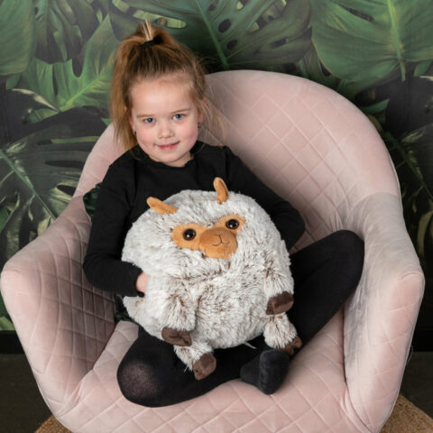 A little girl in the armchair with the alpaca wool pillow and his little hands in his pockets