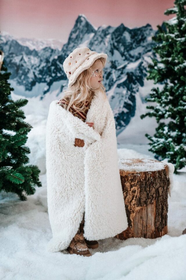 σκηνικο χειμερινό με χιόνια και ένα κοριτσάκι αγκαλιά με την εκρου κουβέρτα και εφέ προβάτου